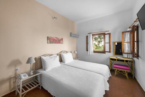 1 dormitorio con 2 camas blancas y TV en Cavo Grosso Bungalows, en Mavrovouni