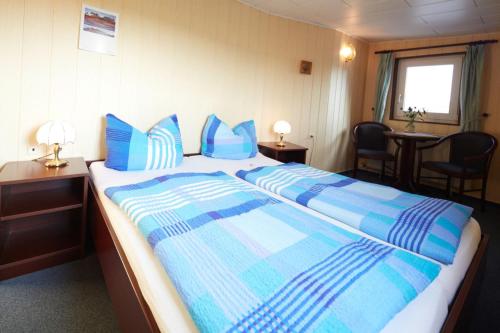 um quarto com uma cama grande e almofadas azuis em Hotelschiff Stinne em Wustrow