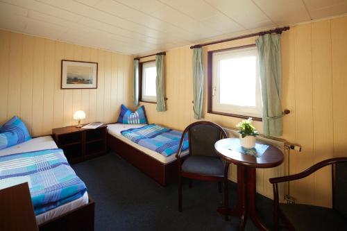 烏斯特羅的住宿－Hotelschiff Stinne，一间设有两张床、一张桌子和一把椅子的房间