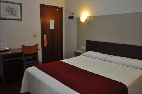 a hotel room with a bed and a desk and a chair at Pension Alameda in San Sebastián