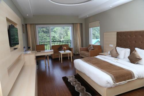 Habitación de hotel con cama grande y escritorio. en The Bliss Palampur, en Pālampur