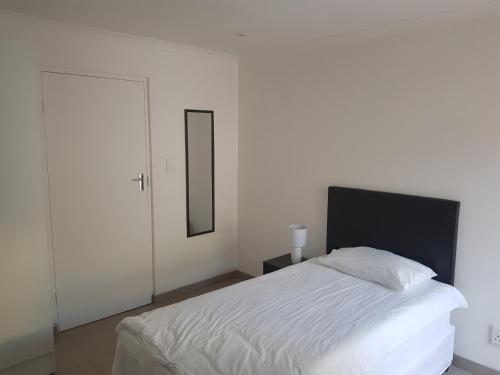 a bedroom with a white bed and a mirror at Fama Lodge Single Rooms in Cape Town