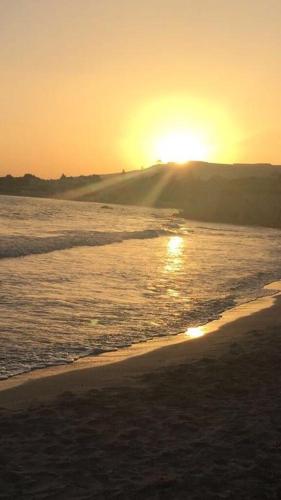a sunset on the beach with a boat in the water at Sweet Home & Apartments in Fontane Bianche