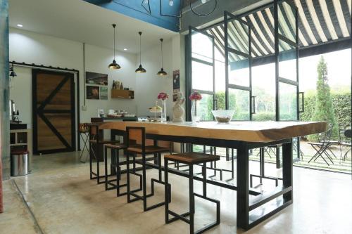 una cocina con una gran mesa de madera y taburetes en Manonnee en Chiang Rai