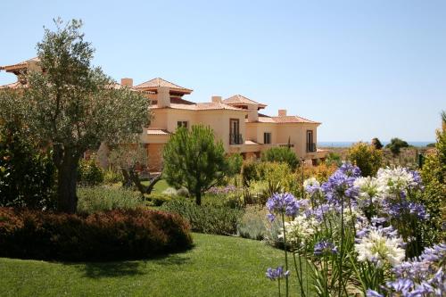 a garden in front of a house with flowers at Monte Rei Golf & Country Club in Vila Nova de Cacela