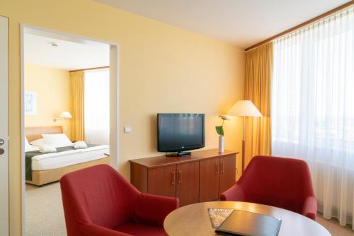 a living room filled with furniture and a tv at Globana Airport Hotel in Schkeuditz
