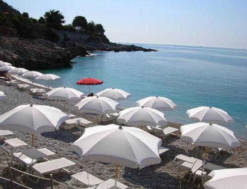 a group of white umbrellas and chairs on a beach at Maison du Citron in Vallecrosia
