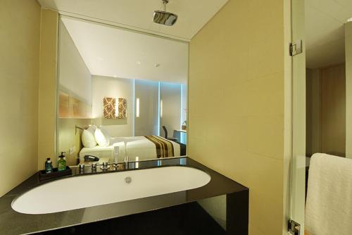 a bathroom with a tub and a bed in a room at Ra Premiere Simatupang Jakarta in Jakarta