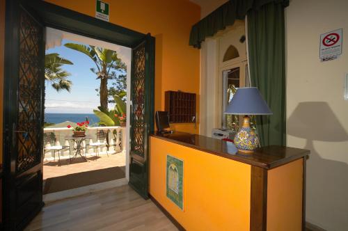 a room with a door leading to a patio with the ocean at Hotel Baia Delle Sirene in Taormina