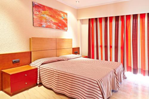a bedroom with a bed with a striped blanket at MLL Caribbean Bay in El Arenal