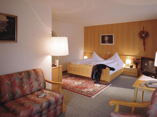 een hotelkamer met een bed en een stoel bij Pension Grissemann in Lech am Arlberg
