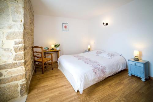 a bedroom with a bed and a table with a chair at Chambres d'hôtes Entre Dolmens et Fontaines in Buzeins