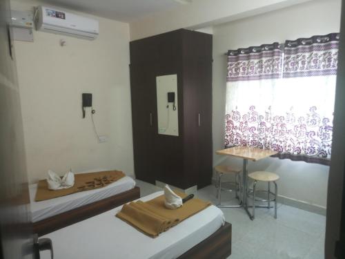 een kamer met 2 bedden, een tafel en een raam bij Sapphire stay in Bangalore