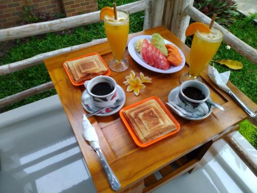 - une table avec des aliments pour le petit-déjeuner et 2 verres de jus d'orange dans l'établissement Angels Bungalow Nusa Penida, à Nusa Penida