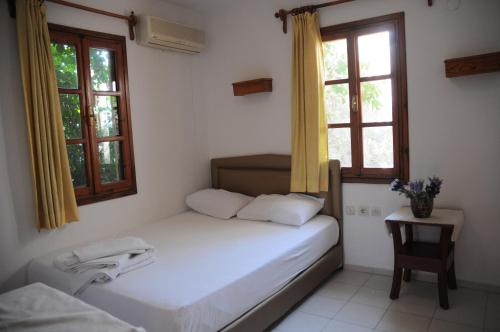 a small bedroom with a bed and two windows at Hotel Gulec in Bodrum City