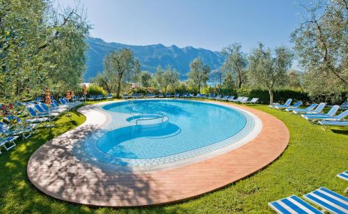 a swimming pool with chairs and mountains in the background at Hotel Ideal in Limone sul Garda
