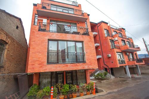 um edifício de tijolos vermelhos com varandas numa rua em Tbilisi LOA Apartment em Tbilisi