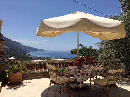 a table and chairs under an umbrella on a balcony at Villa Symbola in Oludeniz