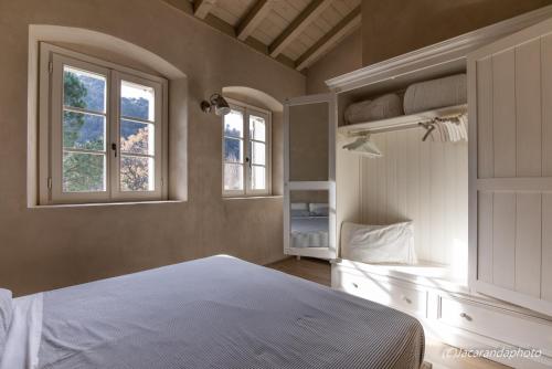 a bedroom with a white bed and two windows at Il Borgo Mediceo in Seravezza