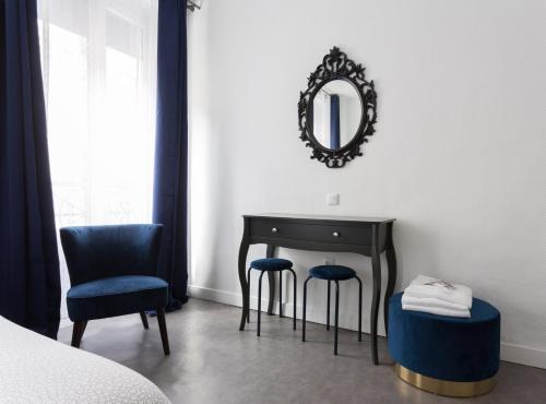 ein Schlafzimmer mit einem Tisch, 2 Stühlen und einem Spiegel in der Unterkunft Hotel Europe BLV in Paris