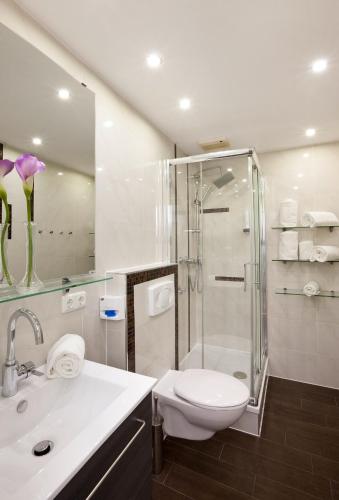 a bathroom with a shower and a toilet and a sink at City Apart Hotel Füssen in Füssen