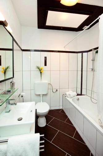 a bathroom with a toilet and a tub and a sink at City Apart Hotel Füssen in Füssen