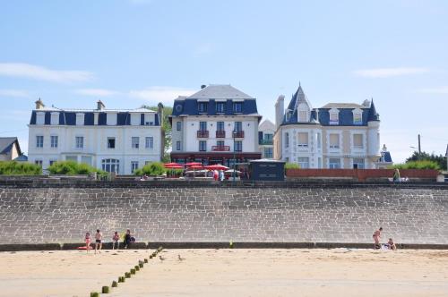 a group of people sitting on the beach near a building at Hôtel Ar Iniz in Saint Malo