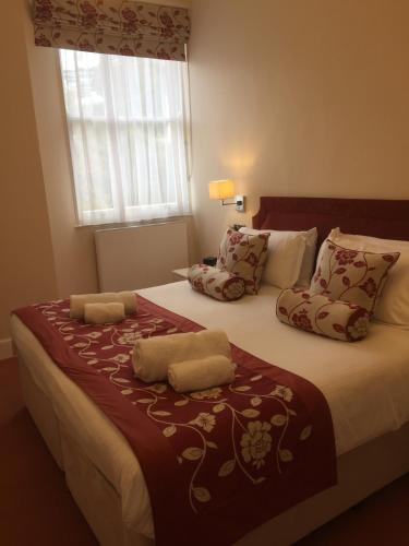 a bedroom with a large bed with pillows and a window at The Osborne Apartments in Torquay