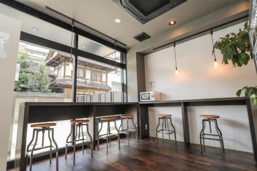 a bar with stools in a room with large windows at EIWA PLACE HOTEL HAKATA - Former Hotel Ninestates Hakata in Fukuoka