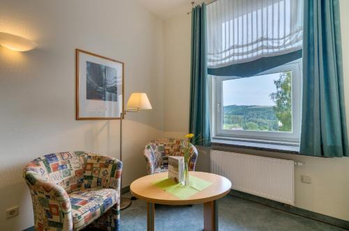 a room with a chair and a table and a window at Kurhotel Bad Schlema in Bad Schlema