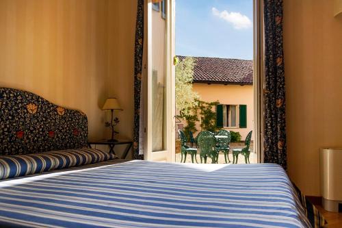 Schlafzimmer mit einem Bett und einem Fenster mit Stühlen in der Unterkunft Hostellerie Du Golf in Pecetto