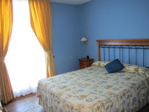 a bedroom with a bed with a blue wall at Hotel Ermintxo in Ea