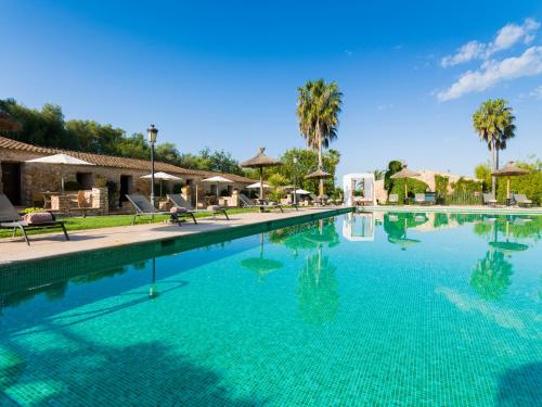 a swimming pool with blue water and palm trees at Sa Bassa Rotja Ecoturisme in Porreres