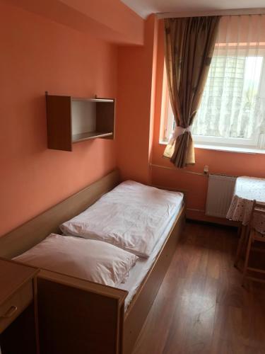 ein kleines Schlafzimmer mit einem Bett und einem Fenster in der Unterkunft Zajazd Batory in Chorzów