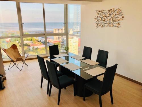 ein Esszimmer mit einem Tisch und Stühlen sowie einem großen Fenster in der Unterkunft Delightful Ocean View Apartment - PH Quartier Del Mar in Panama-Stadt
