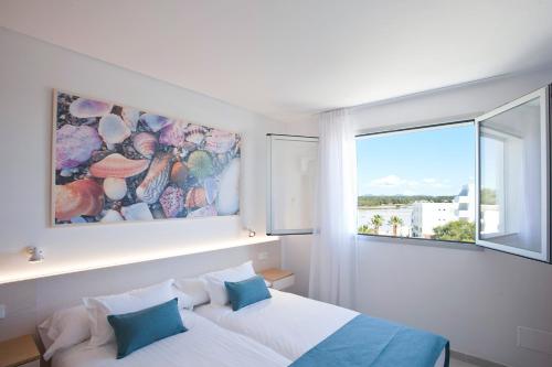 a bedroom with a bed and a large window at Apartaments Posidonia in Colonia Sant Jordi