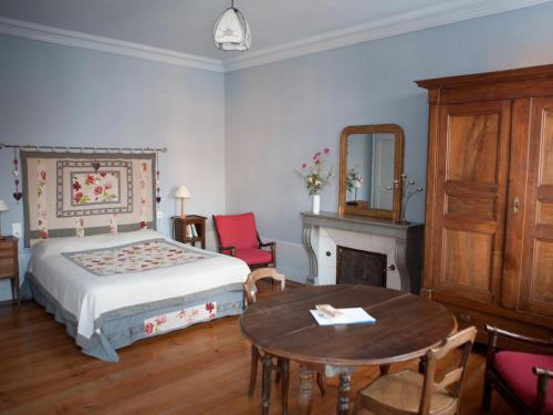 a bedroom with a bed and a table and a fireplace at Le Relais du Passe-Heures in Cenans