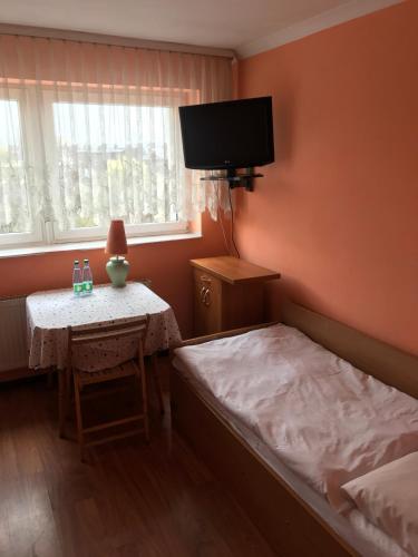a bedroom with a bed and a table and a tv at Zajazd Batory in Chorzów