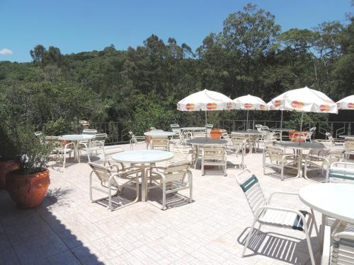 a patio with tables and chairs and umbrellas at Pousada Juriti - Eco Hotel in São Roque