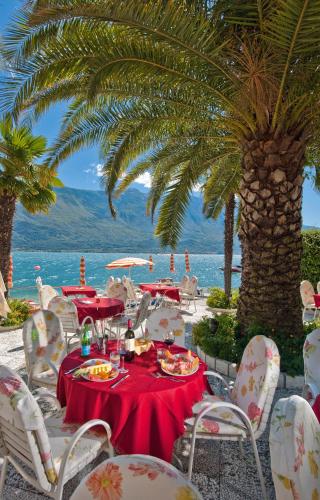 a table with a red tablecloth and chairs and a palm tree at Hotel Ideal in Limone sul Garda