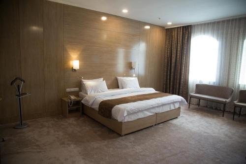 a hotel room with a large bed and a chair at Hotel Uzbekistan in Urganch