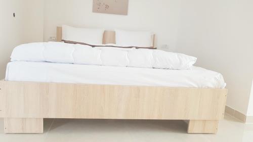 a wooden bed with white sheets and pillows on it at Ema in Vama Veche