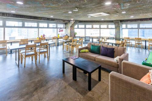 a room with couches and tables and tables and chairs at Busan Popcorn Hostel in Busan