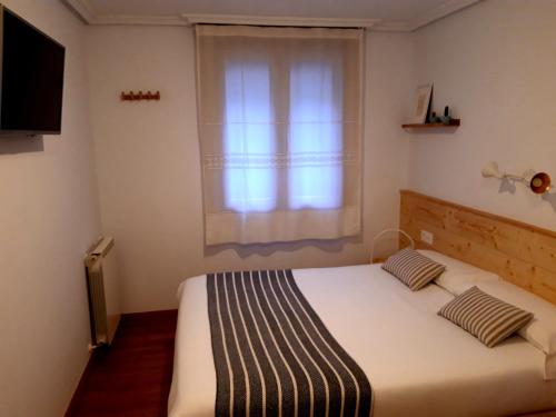a bedroom with a large bed with a window at Pensión Urkia in Donostia-San Sebastián