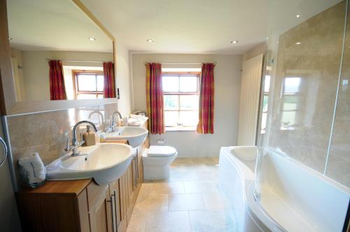 łazienka z 2 umywalkami, wanną i toaletą w obiekcie Green Bank Farmhouse w mieście Lancaster