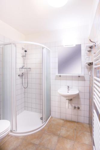 a white bathroom with a shower and a sink at Penzion a vinařství U Vrbů in Hustopeče