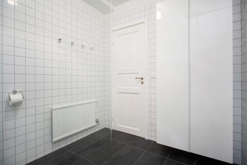 ein weiß gefliestes Bad mit einer weißen Tür in der Unterkunft Thingholt Apartments in Reykjavík