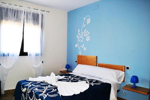 um quarto com uma cama com paredes azuis e uma janela em Casa El lince de Granadilla, Norte provincia Cáceres, WIFI, Parque infantil, HIDROMASAJE, garaje, LAVAVAJILLAS em Zarza de Granadilla