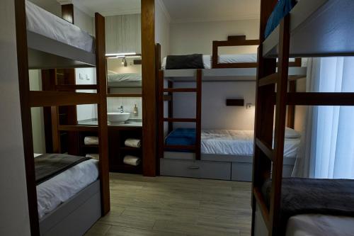 a room with bunk beds and a bathroom with a sink at Memória Charming House in Angra do Heroísmo