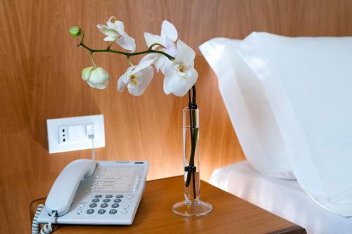 a phone and a vase with white flowers on a table at Park Hotel Centro Congressi in Potenza
